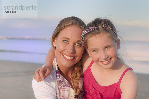 Mutter und Tochter lächeln am Strand