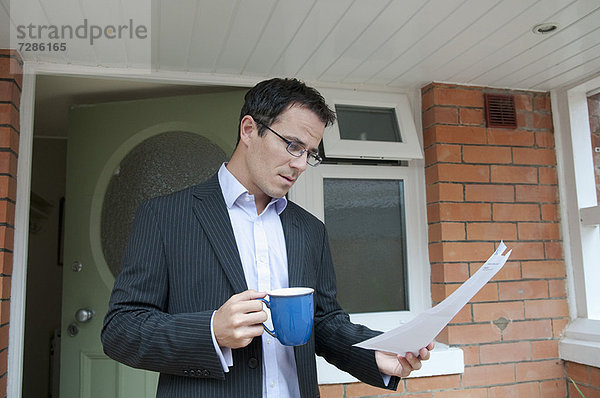 Geschäftsmann beim Lesen mit einer Tasse Kaffee