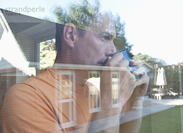 Mann mit Kaffee im Fenster reflektiert