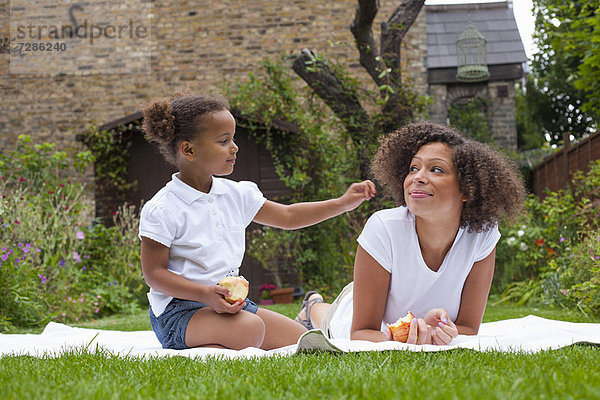 Mutter und Tochter beim Essen im Garten