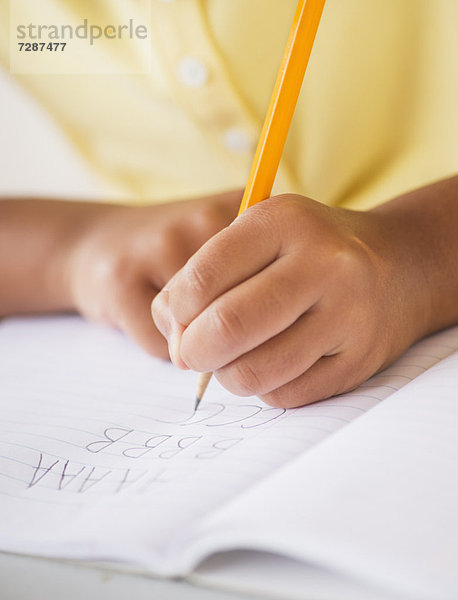 Girl (6-7) doing homework  close-up of hands