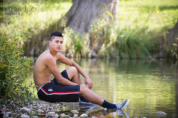 USA  Texas  Teenage boy sitting at Frio River  portrait