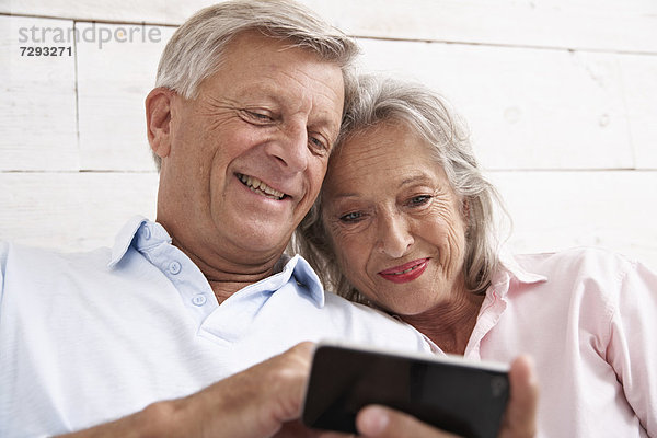 Spain  Senior couple using mobile phone  smiling