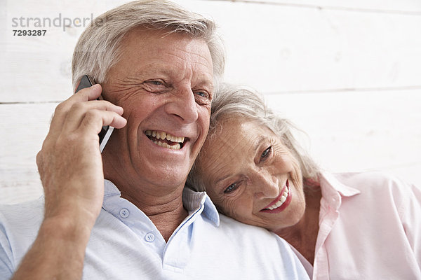 Spanien  Seniorenpaar im Gespräch mit dem Handy  lächelnd