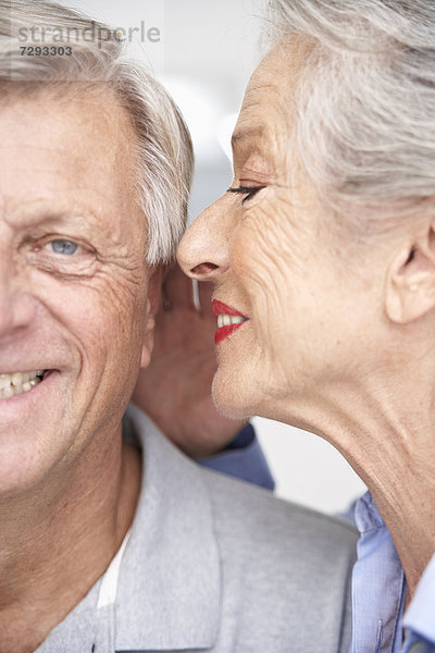 Spain  Senior woman whispering into ear of man  smiling