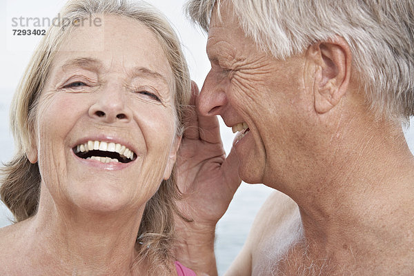 Spanien  älterer Mann flüstert ins Ohr der Frau  lächelnd
