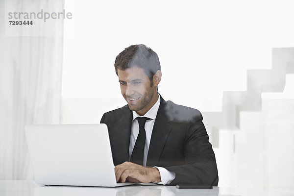 Spain  Businessman using laptop  smiling