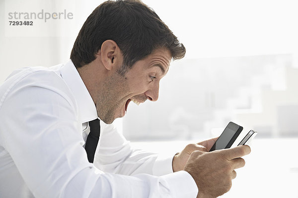 Spain  Businessman confused of using two mobile phone  smiling