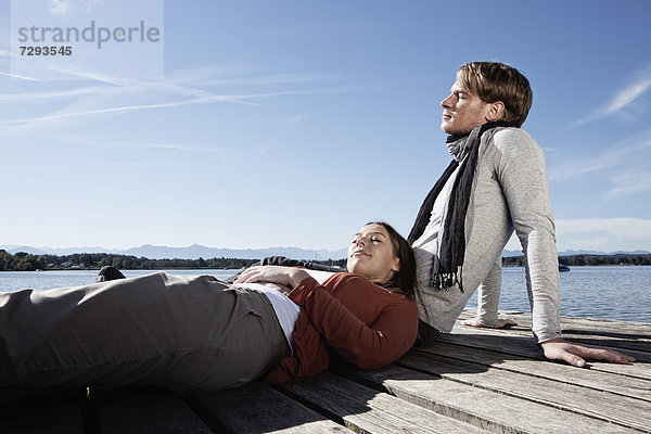 Germany  Bavaria  Couple sitting on jetty at Lake Starnberg