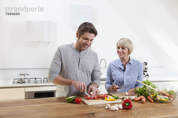 Germany  Bavaria  Munich  Mature couple chopping vegetables in kitchen  smiling