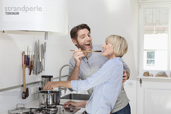 Reife Frau beim Kochen während der Fütterung des Mannes