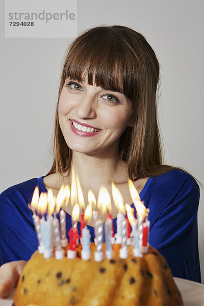 Young woman showing birthday cake  smiling  portrait
