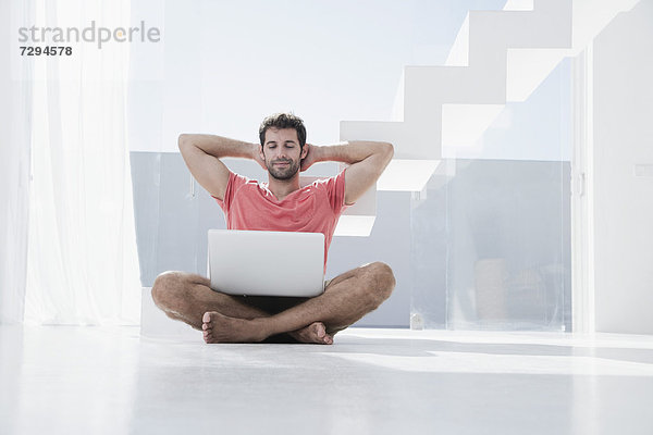 Spain  Mid adult man sitting on floor with laptop