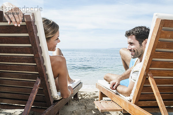 Spain  Mid adult couple relaxing on beach chair