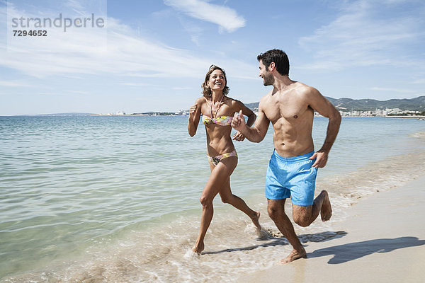 Spain  Mid adult couple running on beach