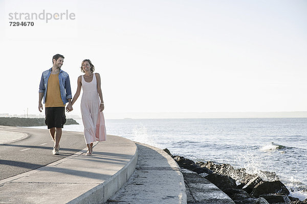 Spain  Mid adult couple walking along coast