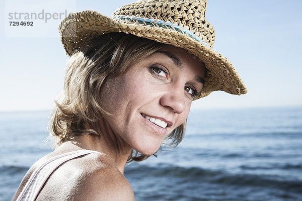 Spain  Mid adult woman with straw hat at Atlantic Ocean  smiling