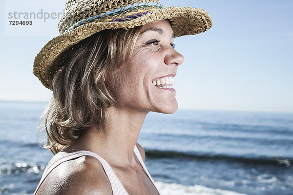 Spanien  Mittlere erwachsene Frau mit Strohhut am Atlantik  lächelnd