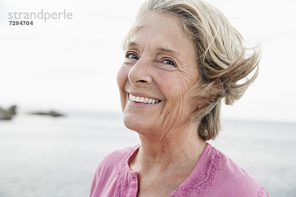 Spain  Senior woman smiling at Atlantic ocean