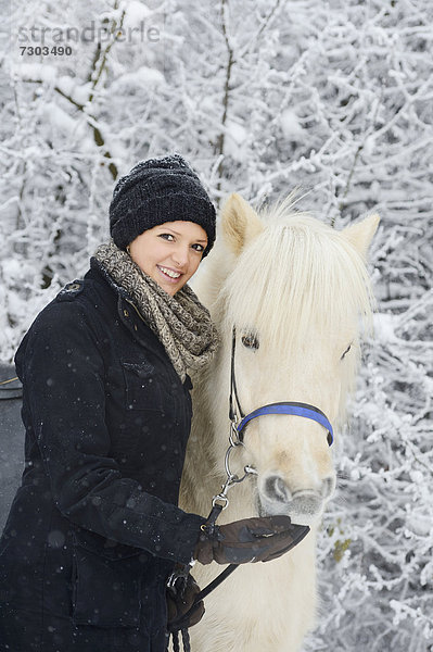 Junge Frau mit Pferd im Schnee