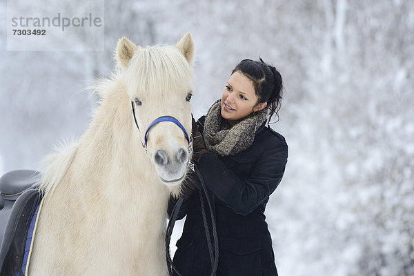 Junge Frau mit Pferd im Schnee