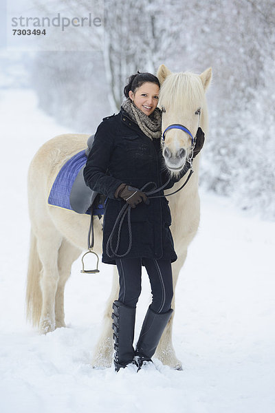 Junge Frau mit Pferd im Schnee