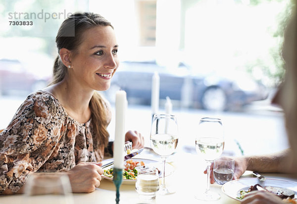 Fröhliche junge Frau beim Anblick eines Freundes am Restauranttisch