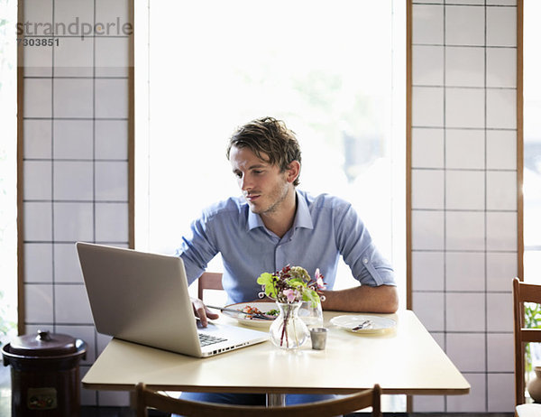 Junger Mann am Restauranttisch mit Laptop