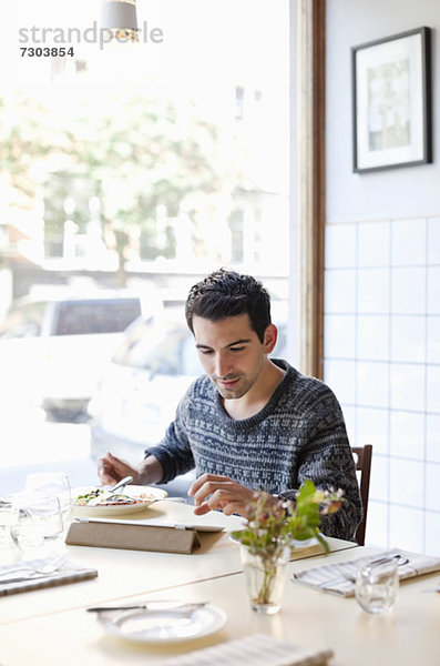 Junger Mann am Restauranttisch mit digitalem Tablett