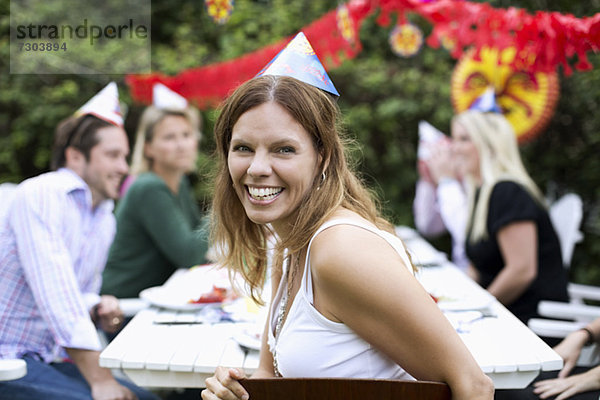 Porträt einer fröhlichen mittleren erwachsenen Frau  die mit Freunden im Hintergrund Krebspartys feiert.