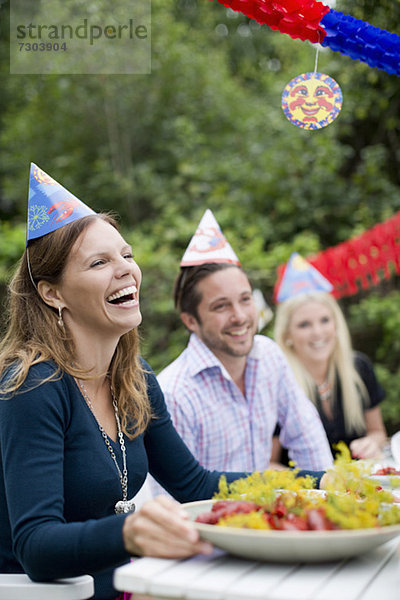 Fröhliche junge Frau mit Freunden am Esstisch bei der Krebsparty