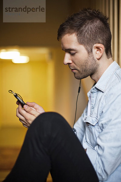 Seitenansicht des jungen Kaukasiers beim Musikhören per Handy