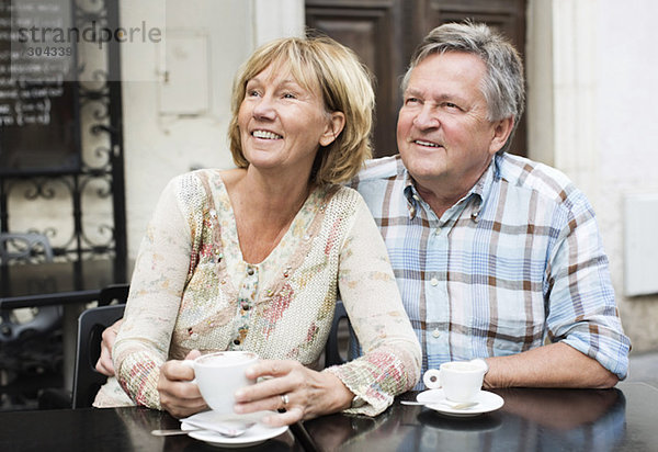Ein glückliches Paar beim Kaffeetrinken beim Blick auf den Tisch