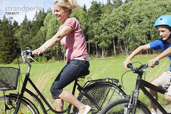 Glückliche reife Frau und Sohn beim Fahrradfahren in den Ferien