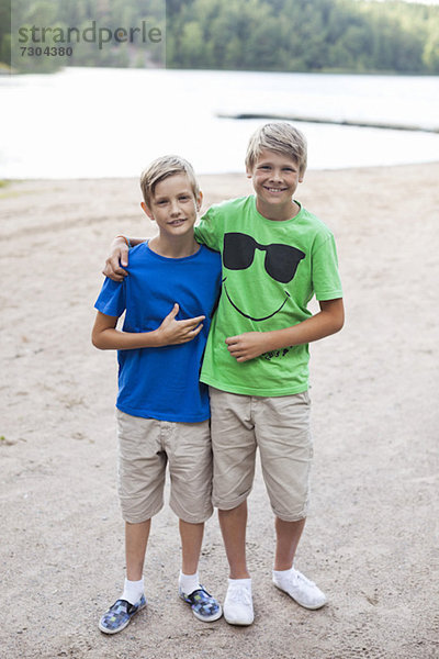 Porträt von glücklichen Brüdern  die zusammen am Strand stehen