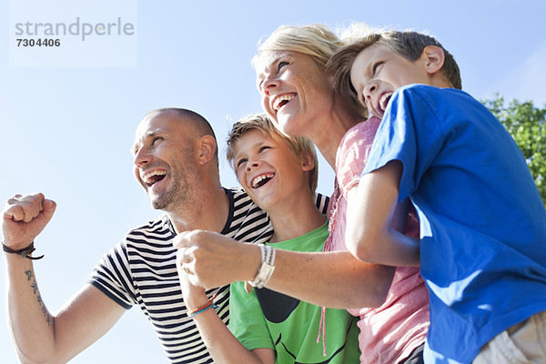 Tiefblick auf eine glückliche kaukasische Familie  die gemeinsam gegen den klaren Himmel genießt.