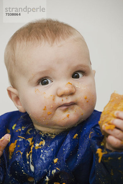 Ein kleiner Junge mit Essen im Gesicht.