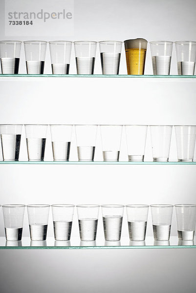 Reihen von Gläsern mit unterschiedlichen Wassermengen und eine mit Bier gefüllt
