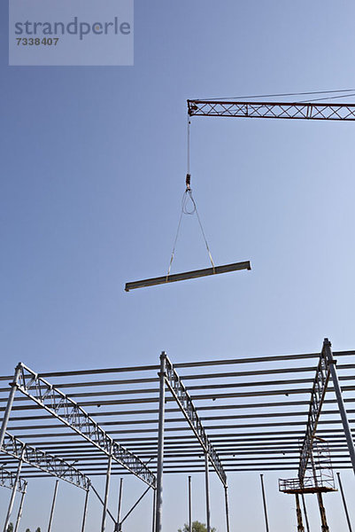 Kran senkt Stahlträger zum Konstruktionsrahmen hin ab
