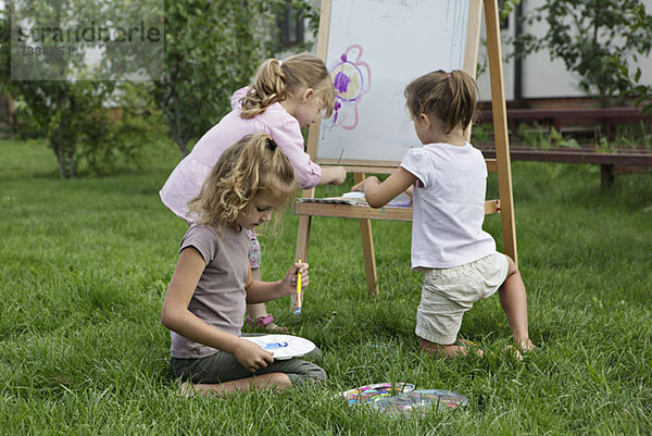 Drei junge Mädchen malen im Hinterhof