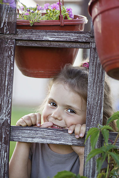 Ein junges lächelndes Mädchen  das durch ein Gitter schaut.