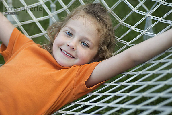 Ein junges  fröhliches Mädchen  das auf einer Hängematte liegt.