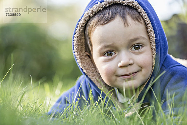 Ein kleiner Junge mit Kapuzenjacke im Gras