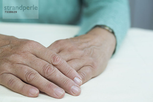 Eine reife Frau sitzt an einem Tisch  Nahaufnahme der Hände