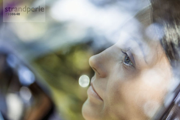 Eine junge Frau  die nachdenklich aus dem Fenster eines stationären Autos schaut.