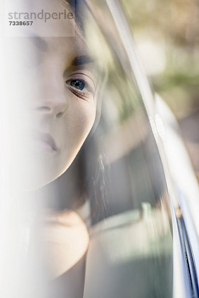 Eine junge Frau in einem stationären Auto  die ruhig aus dem Fenster schaut.
