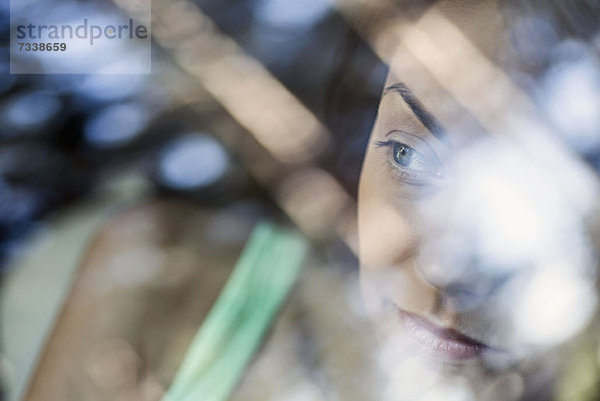 Eine junge Frau  die nachdenklich aus dem Fenster eines stationären Autos schaut.