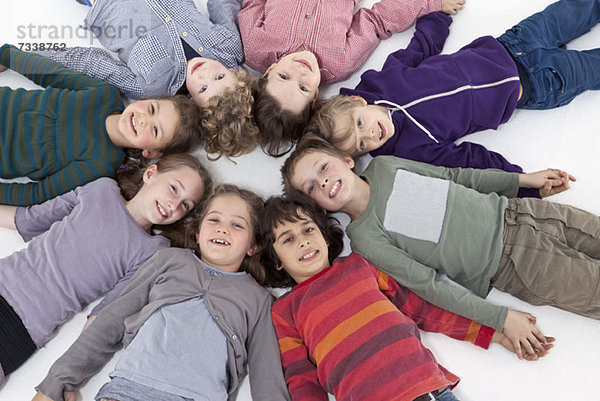 Eine Gruppe von Kindern  die im Kreis auf dem Rücken liegen und den Kopf berühren.