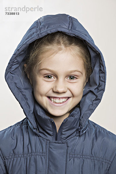 Ein fröhliches  junges Mädchen in einer Winterjacke.
