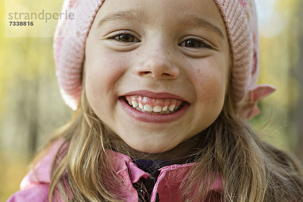 Ein fröhliches junges Mädchen mit rosa Strickmütze und Grinsen